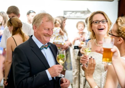 Hochzeitsreportage in Muenchen: Lachende Gaeste mit Getraenken bei einer Hochzeit. Stimmungsvoll und gesellig.