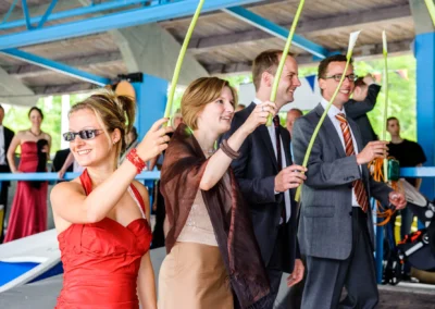 Gäste halten Stäbe bei einer Hochzeit nahe Eibsee, festlich gekleidet, Hochzeitsreportage von Hochzeitsfotograf.