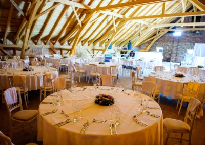 Gedeckte Hochzeitstafeln in rustikalem Saal auf Gut Thurnsberg, elegantes Ambiente bei Hochzeitsreportage in Oberbayern.