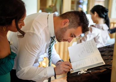 Mann schreibt in Gaestebuch bei Hochzeit im Gasthof Sauerlach-Arget, Hochzeitsfotografie von Hochzeitsreportage.