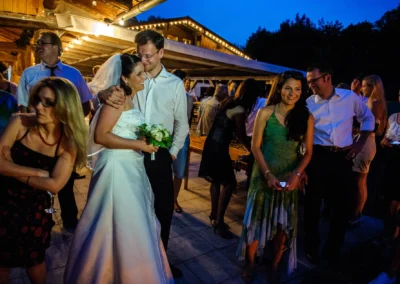 Brautpaar bei der Hochzeit auf der Terrasse der Sprengenoder Alm, umgeben von lachenden Gaesten.