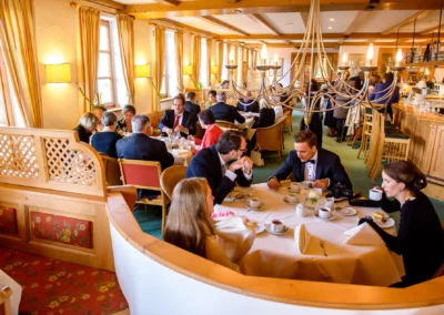 Gäste bei der Hochzeitsfeier in Waakirchen genießen ein festliches Essen unter einem Kronleuchter.