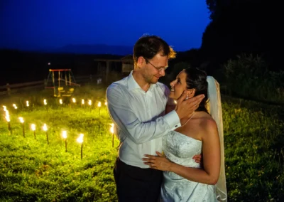 Brautpaar in inniger Umarmung bei Nacht, umgeben von Fackeln, in Eurasburg bei Wolfratshausen. Hochzeitsfotografie.