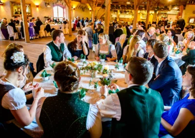 Gäste bei einer Hochzeit in traditioneller Tracht in einem Saal in Bruckmühl, aufgenommen von Hochzeitsfotograf.