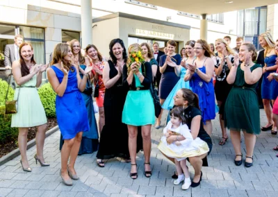 Brautstrausswurf bei Hochzeit im Hotel Vier Jahreszeiten Starnberg, Gaeste lachen und klatschen begeistert.