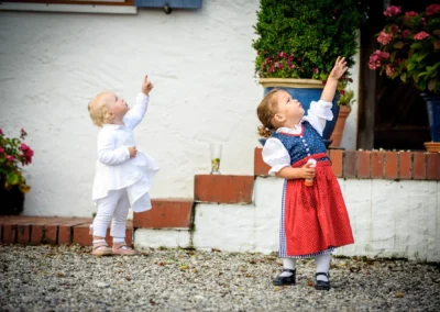 Kinder in traditioneller Kleidung zeigen nach oben bei einer Hochzeit auf Gut Thurnsberg, fotografiert in Oberbayern.