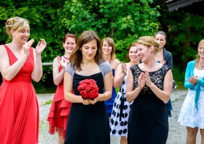 Gruppe von Frauen gratuliert Brautjungfer mit Blumenstrauss bei Hochzeit nahe Zugspitze. Hochzeitsfoto.