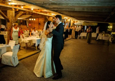 Brautpaar tanzt in rustikalem Festsaal, Hochzeitsreportage auf Sprengenöder Alm, Gaeste im Hintergrund.
