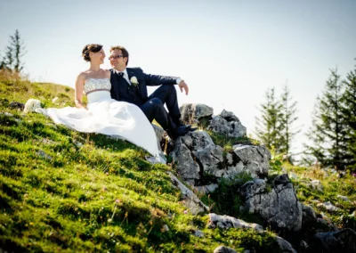 Brautpaarfoto im Freien auf Felsen bei Sonnenschein, Sonnenalm Kampenwand, Hochzeitsfotografie in Oberbayern.
