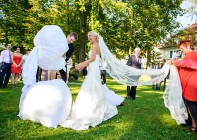 Brautpaar lacht mit Gaesten im Garten bei Hochzeitsfeier in Oberambach. Hochzeitsfoto zeigt froehlichen Moment.