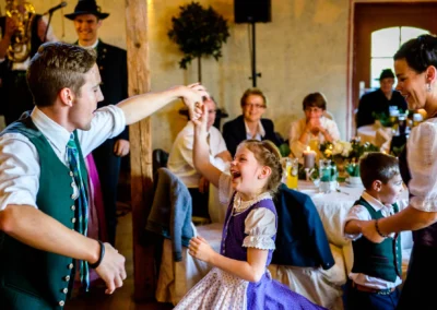Kind tanzt bei Hochzeit in Hofgut zur Mühle, traditionell gekleidet. Hochzeitsreportage zwischen München und Rosenheim.