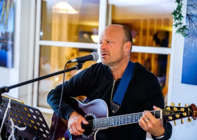 Musiker spielt Gitarre und singt bei einer Hochzeit in Uffing, aufgenommen von Hochzeitsfotograf.