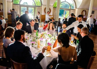 Gedeckter Tisch bei einer Hochzeitsfeier im Seehaus, mit Gästen im Englischen Garten in München. Hochzeitsreportage.