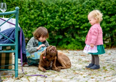 Kinder spielen mit Hund bei Hochzeitsfeier in Waakirchen. Lebendige Hochzeitsreportage mit Tieren und Kindern.