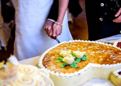 Brautpaar schneidet Hochzeitstorte in Herzform bei Feier in Holzham. Hochzeitsfoto einfängt besonderen Moment.
