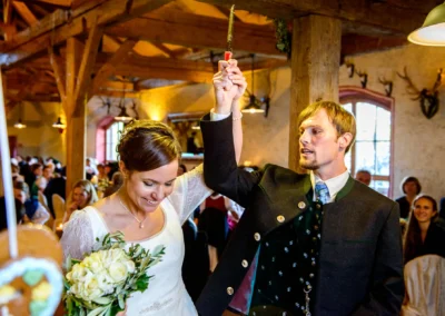 Brautpaar hebt Messer, Brautstrauss in Hofgut zur Muehle. Hochzeitsreportage zeigt freudige Momente.