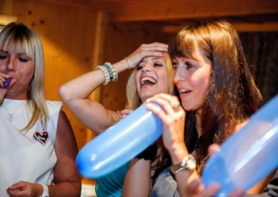 Frauen blasen Luftballons auf einer Hochzeit in Arget. Freude und Lachen bei der Hochzeitsreportage eingefangen.