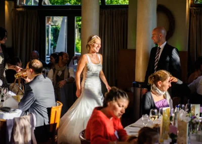 Braut in festlichem Kleid bei einer Hochzeitsfeier in Schwabing, umgeben von Gästen. Hochzeitsfotografie in München.