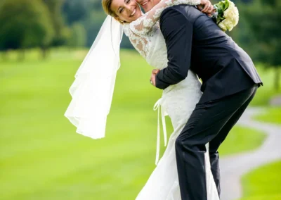 Brautpaar-Shooting auf gruenem Feld in Waakirchen, lachend und umarmt. Hochzeitsfoto nahe Tegernsee.