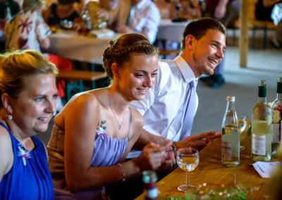 Gäste lachen bei einer Hochzeit in Oberbayern, nahe Rosenheim. Hochzeitsfoto zeigt fröhliche Stimmung am Tisch.