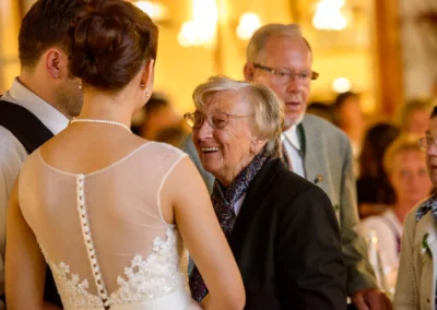Brautleute und Gaeste lachen bei einer Hochzeitsfeier nahe Schliersee. Hochzeitsreportage in entspannter Atmosphaere.