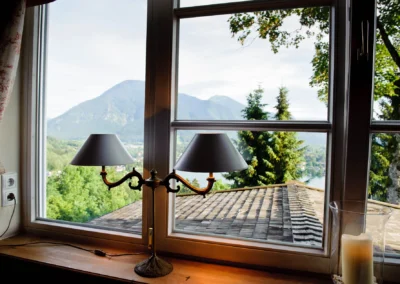 Blick aus einem Fenster im Leeberghof am Tegernsee mit Lampe im Vordergrund, ideal als Hochzeitsfotografie.