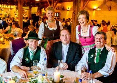 Gruppe von Personen in Trachten bei einer Hochzeitsfeier im Hofgut zur Muehle, herzliches Lachen und Feststimmung.