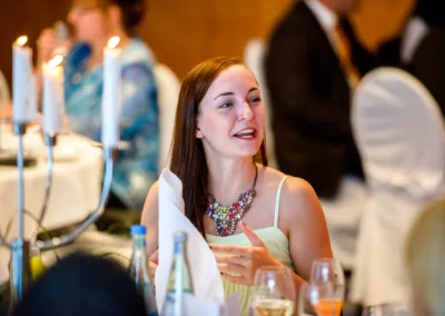 Gäste bei einer Hochzeit im Hotel 4 Jahreszeiten, Starnberg, lachen und genießen das Dinner bei Kerzenlicht. Hochzeitsfotografie.
