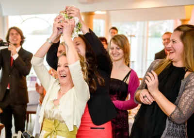 Hochzeitsreportage am Tegernsee: Gäste lachen und fangen den Brautstrauss, festgehalten von einem Hochzeitsfotografen.