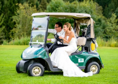 Brautpaar in einem Golfcart bei der Hochzeitsreportage nahe Waakirchen, lachend und ausgelassen auf der Wiese.