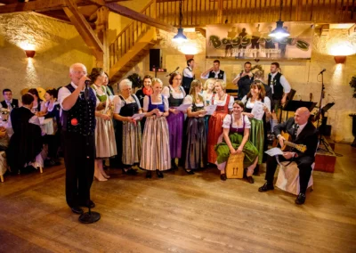 Gruppe von Personen in Tracht bei einer Hochzeitsfeier in Bruckmuehl, musikalische Unterhaltung. Hochzeitsfotografie.
