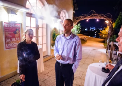 Gäste bei einer Hochzeit in Hugos Beach Club, rauchen und unterhalten sich draußen, Abendstimmung. Hochzeitsfoto.