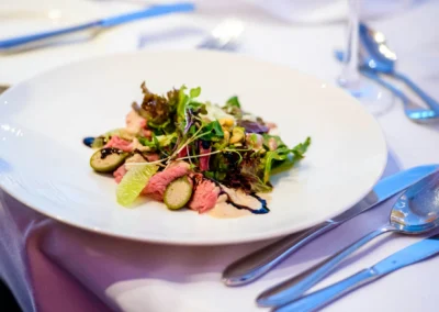 Hochzeitsreportage in Starnberg: Elegantes Hochzeitessen mit Fleisch und Salat auf weissem Teller, Vier Jahreszeiten.