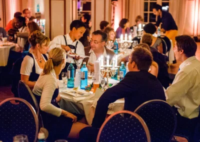Gäste bei einer Hochzeitsfeier am Starnberger See genießen ein festliches Abendessen bei Kerzenlicht.