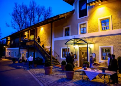 Gäste bei einer Hochzeit am Abend bei Hofgut zur Muehle, beleuchtete Location mit Plaudernden auf der Terrasse.