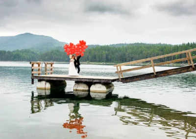 Brautpaar mit roten Luftballons auf einem Steg am Eibsee, Hochzeitsfotograf nahe Garmisch.
