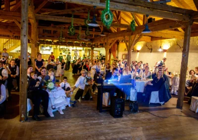 Gäste genießen Hochzeitsfeier in rustikalem Saal im Hofgut zur Mühle, festgehalten von einem Hochzeitsfotografen.