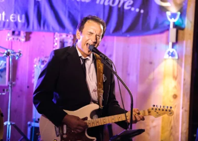 Musiker singt und spielt Gitarre bei Hochzeit in Sauerlach, festliche Stimmung. Hochzeitsfotografie im Landgasthof.