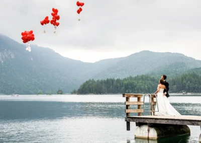 Brautpaar am Steg mit roten Luftballons am Eibsee, Aufnahme bei einer Hochzeit nahe Garmisch.
