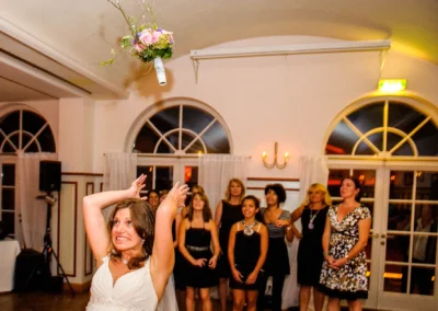 Braut wirft Brautstrauss bei Hochzeitsfeier, Gaeste schauen zu. Hochzeitsfoto aufgenommen in Hugos Beach Club Starnberg.