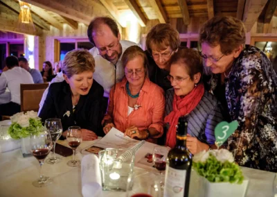Gruppe von Gaesten bei einer Hochzeit im Landgasthof Schmuck, Sauerlach, liest freudig in einem Buch.