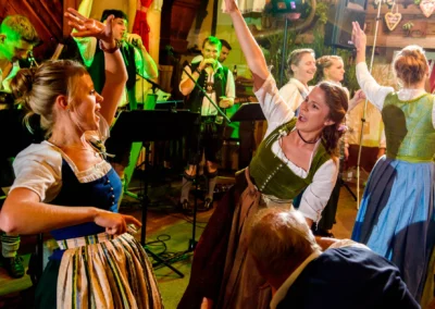 Tanzende Gaeste in Tracht bei einer Hochzeit in Hofgut zur Muehle. Stimmungsvoll und traditionell. Hochzeitsfotografie.