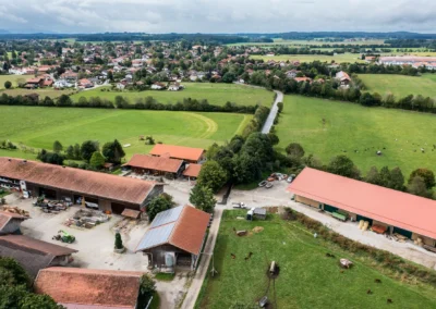 Luftaufnahme mit Drohne eines Bauernhofs bei einer Hochzeit südlich von München, umgeben von Feldern und Wald.