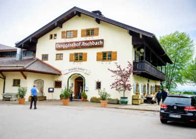 Berggasthof Aschbach bei einer Hochzeit, Gäste betreten das Gebäude. Perfekt für Hochzeitsfotografie südlich München.