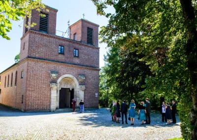Hochzeitsfoto vor der Christuskirche in Gauting nahe Muenchen, Gruppe von Gaesten versammelt im Sommerlicht.