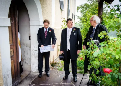 Drei elegant gekleidete Herren bei einer Trauung in der Wallfahrtskirche Wilparting im Kreis Miesbach. Hochzeitsfotografie.