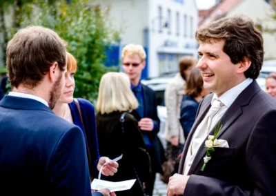 Personen in festlicher Kleidung unterhalten sich bei der kirchlichen Trauung in Neuburg an der Donau.