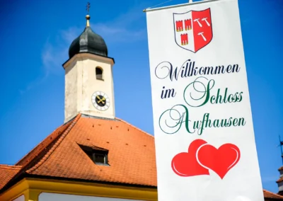 Kirchturm und Willkommensschild bei kirchlicher Trauung im Schloss Aufhausen nahe Muenchen.