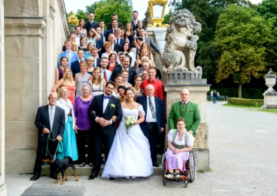 Gruppenfoto einer Hochzeit in Nymphenburg mit Brautpaar und Gaesten auf einer Treppe, Hochzeitsfotografie in Muenchen.