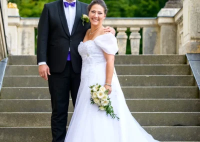 Brautpaar auf Steintreppe von Schloss Nymphenburg. Hochzeitsportrait in Muenchen.